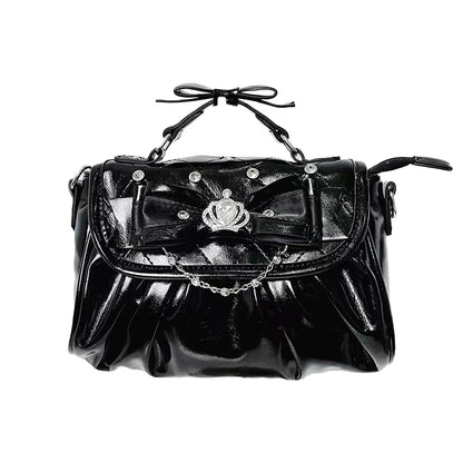 Black handbag with decorative bow and chain on a white background