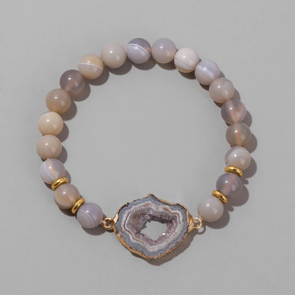 Beaded bracelet with a geode charm on a light grey background