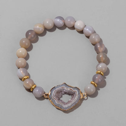 Beaded bracelet with a geode charm on a light grey background