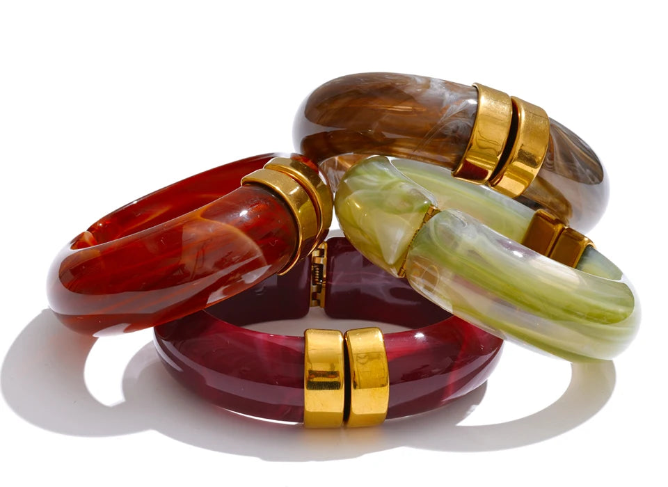 Set of three colourful bracelets with gold accents on a white background
