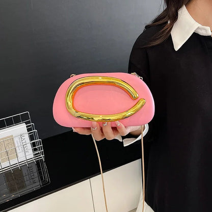 Person holding a pink clutch with gold accents against a dark background