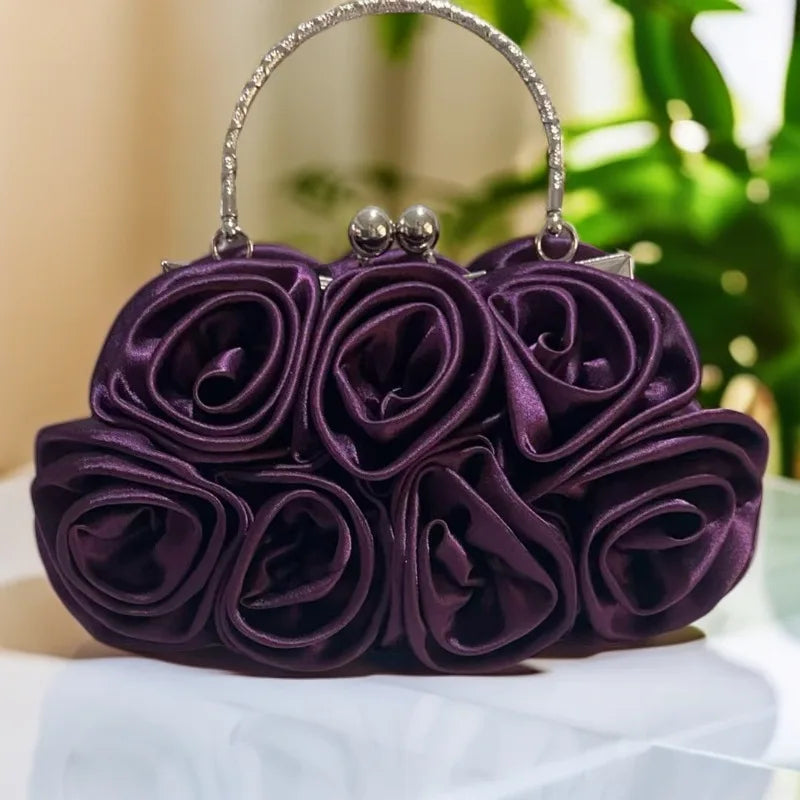 Purple rose-shaped handbag on a white surface with a blurred green background