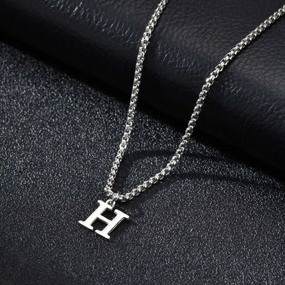 Silver necklace with a 'H' pendant on a black textured surface