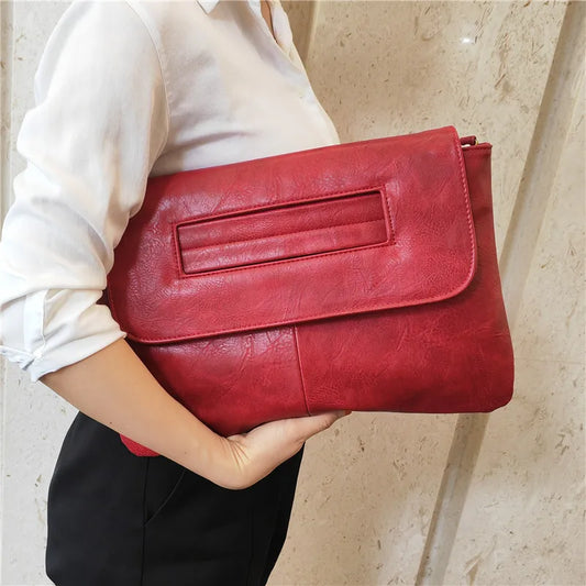 Red clutch bag held by a person against a neutral background