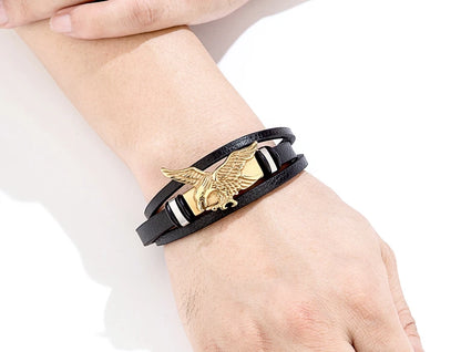 Black leather bracelet with gold eagle emblem on a wrist against a white background