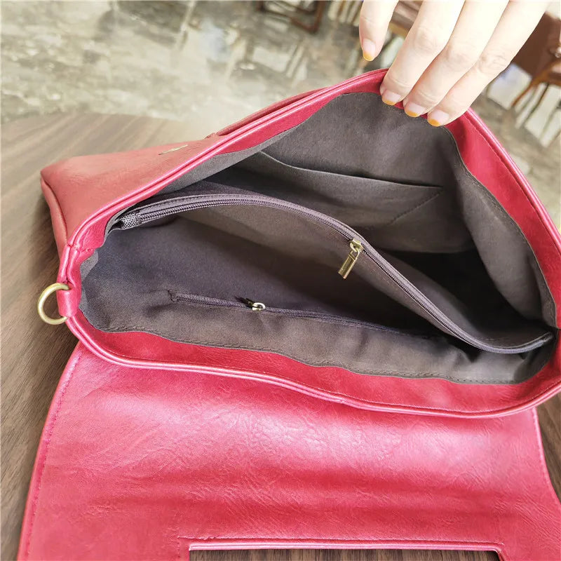 Red handbag with a gold zipper being opened on a wooden surface.