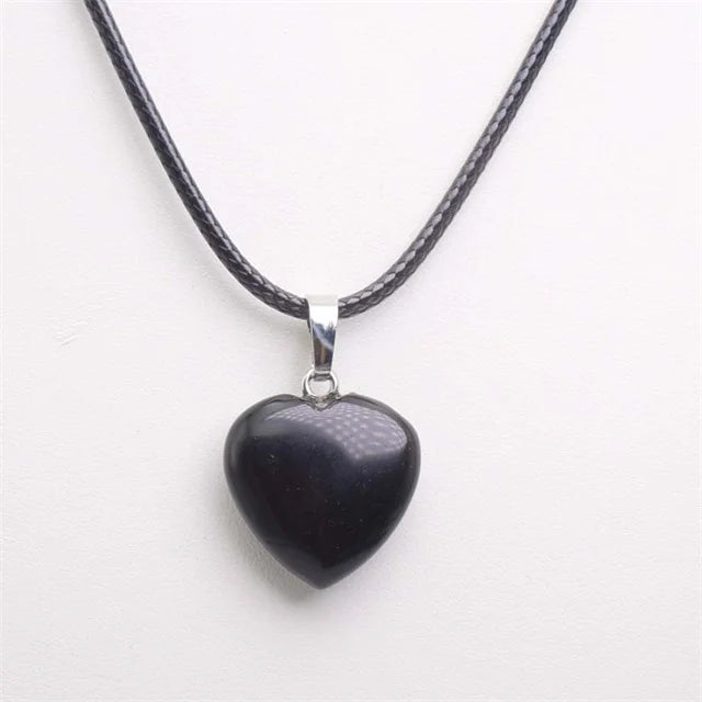 Heart-shaped black pendant on a black cord against a white background