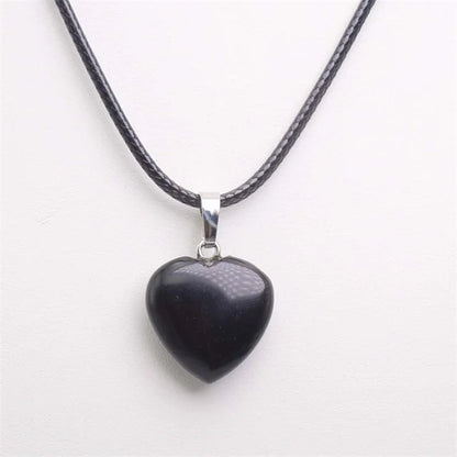 Heart-shaped black pendant on a black cord against a white background