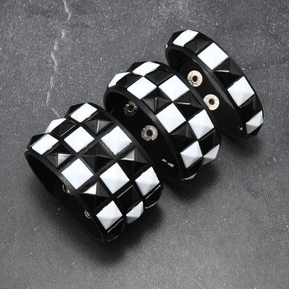 Black and white checkered bracelet with pyramid studs on a dark surface