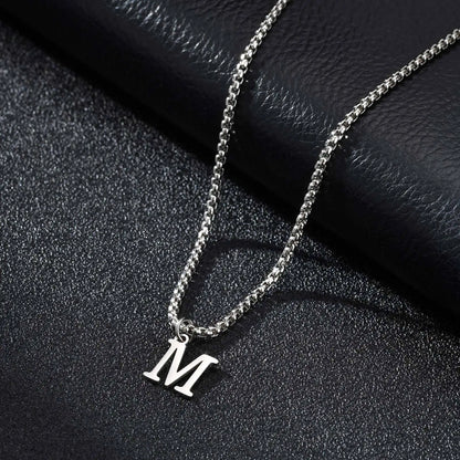 Silver necklace with a 'M' pendant on a black textured surface