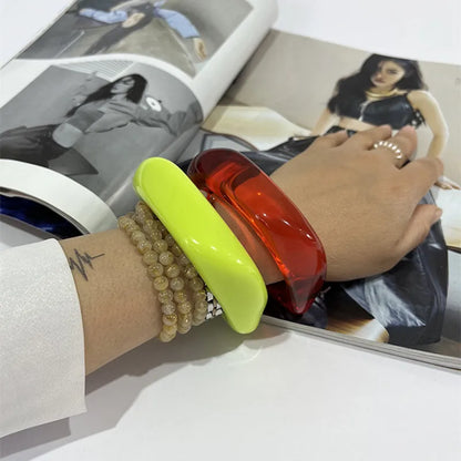 Hand wearing a red and green bangle with a magazine in the background