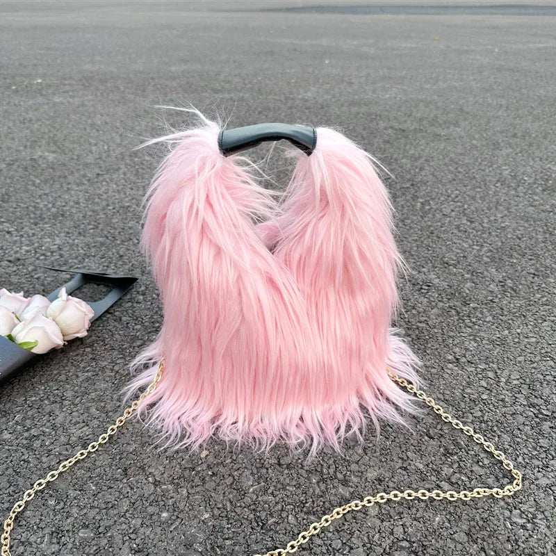 Pink fluffy handbag with a chain on a grey surface