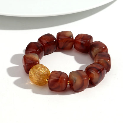Bracelet with brown marbled beads and a gold bead on a white background