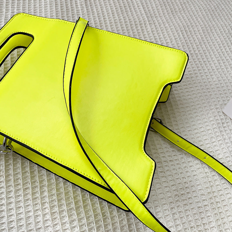 Neon yellow handbag on a textured white surface