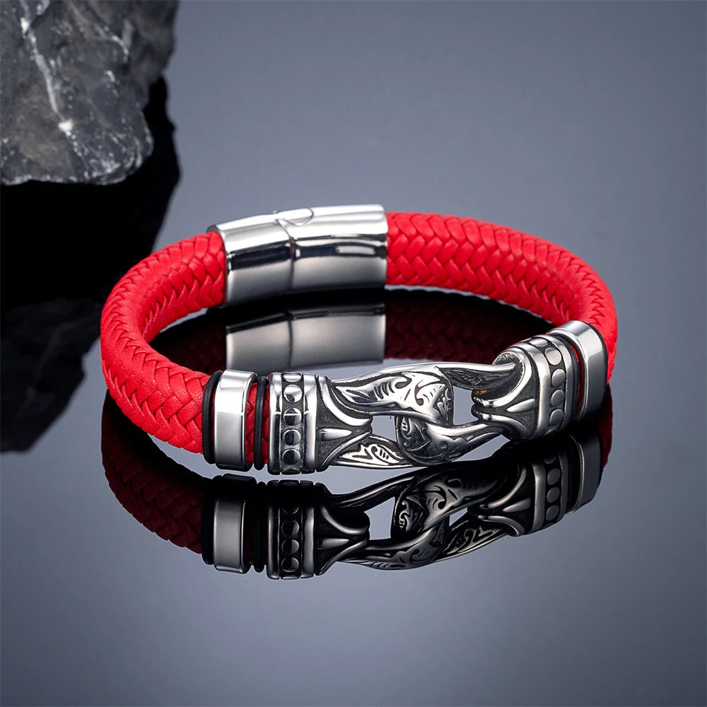 A red braided leather bracelet with polished silver-tone metal accents and an engraved decorative clasp, displayed on a reflective dark surface.
