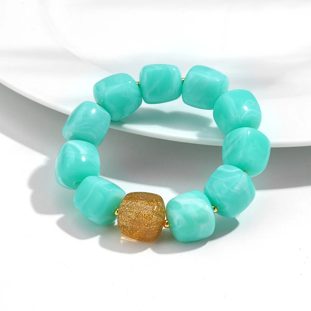Turquoise beaded bracelet with a gold accent on a white background