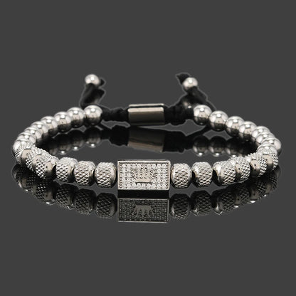 Silver beaded bracelet with a clasp on a reflective surface