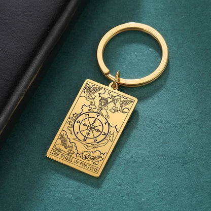 Gold keychain with tarot card design on a teal surface