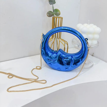 Blue crescent handbag with a gold chain on a white surface.