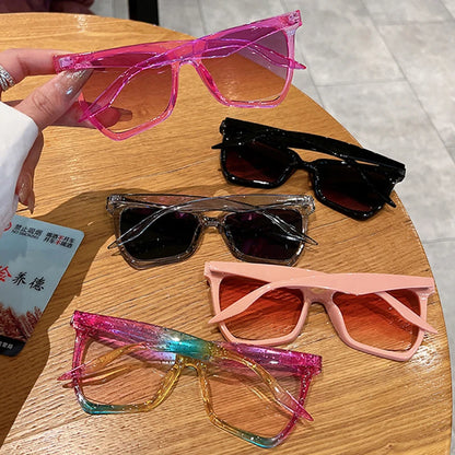 Colourful sunglasses on a wooden table with a hand holding one pair.