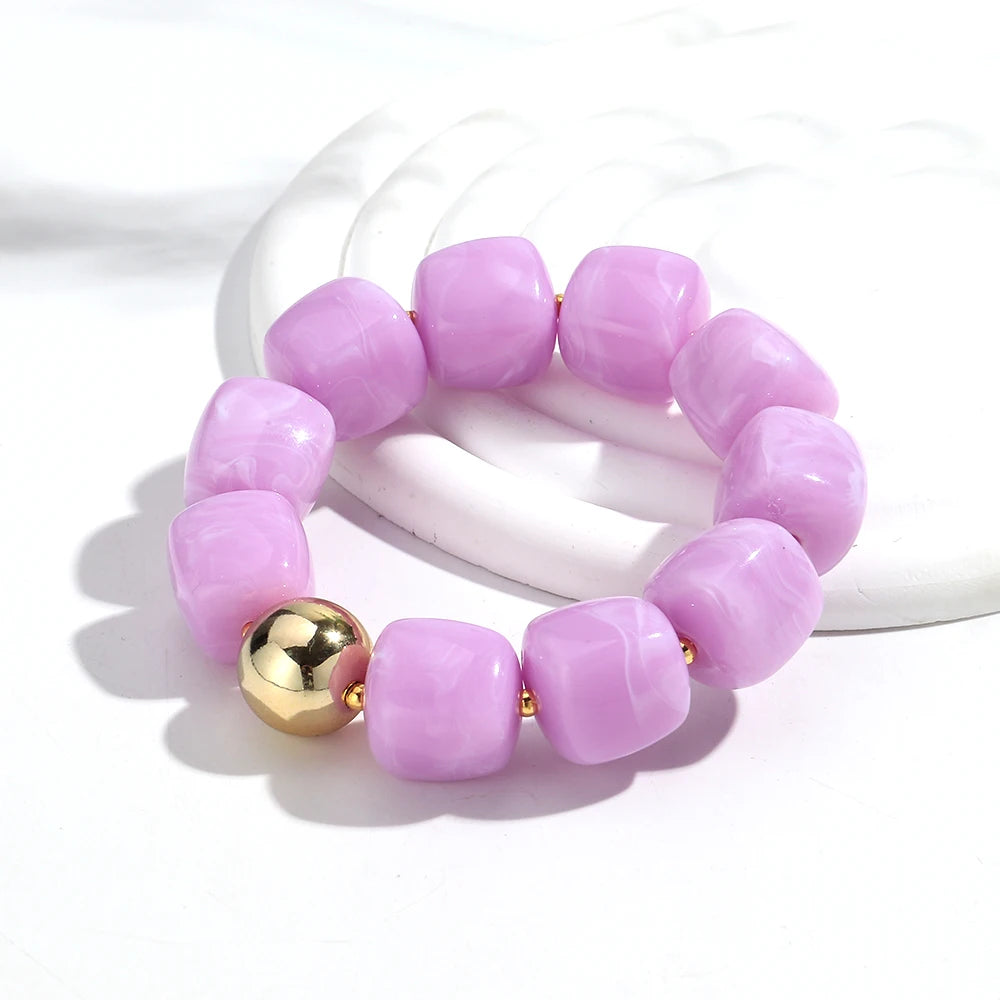 Purple beaded bracelet with a gold bead on a white background