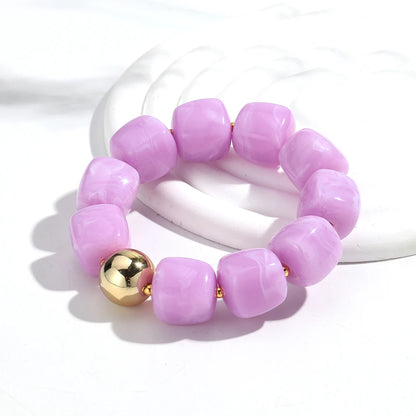 Purple beaded bracelet with a gold bead on a white background