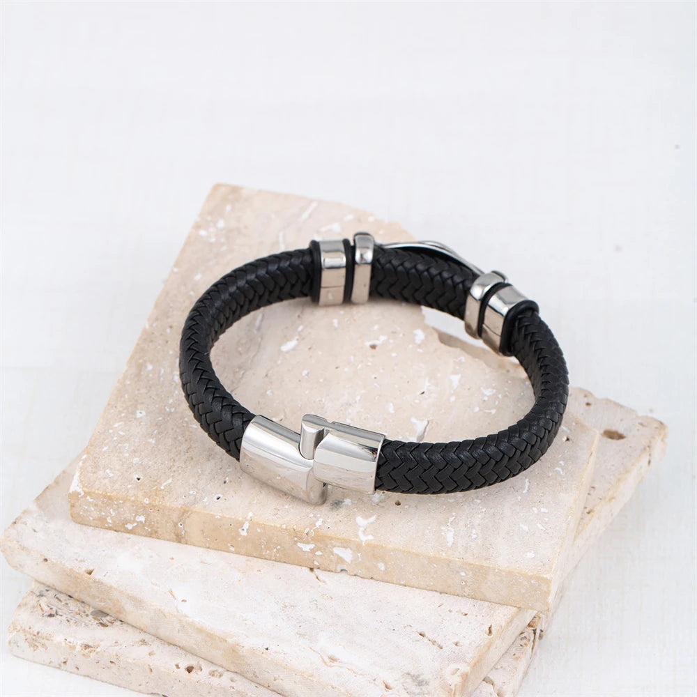 Black braided leather bracelet with silver metal clasps on a stone surface