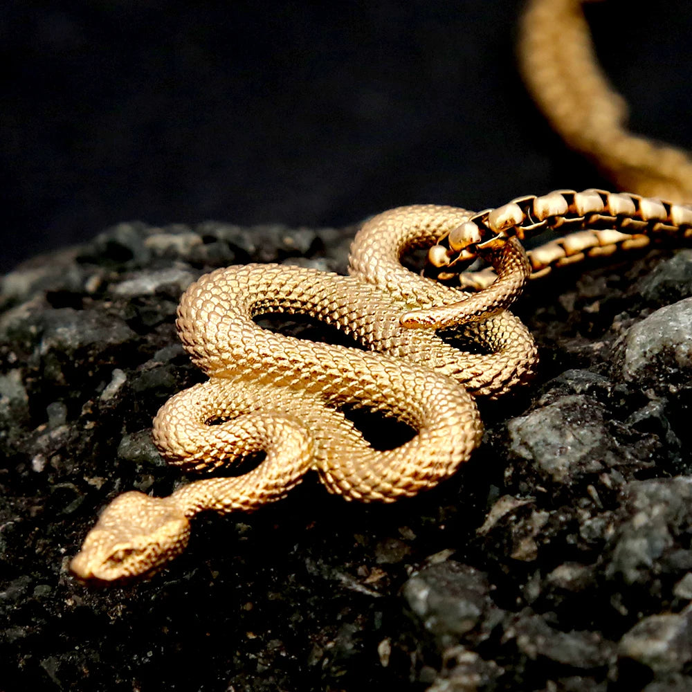 Gold snake-shaped necklace on a dark textured surface