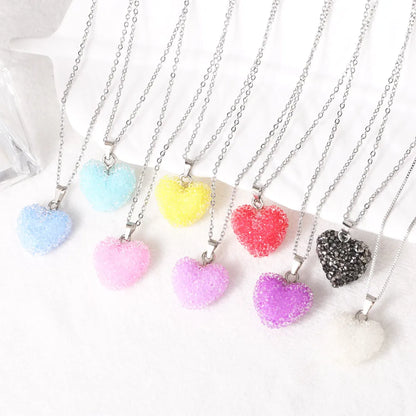 Colourful heart-shaped pendants on silver chains against a white background