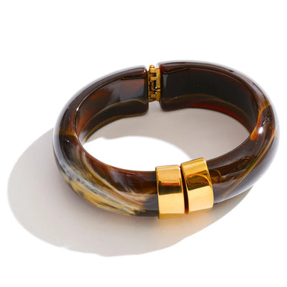 Brass bangle with gold clasp on a white background