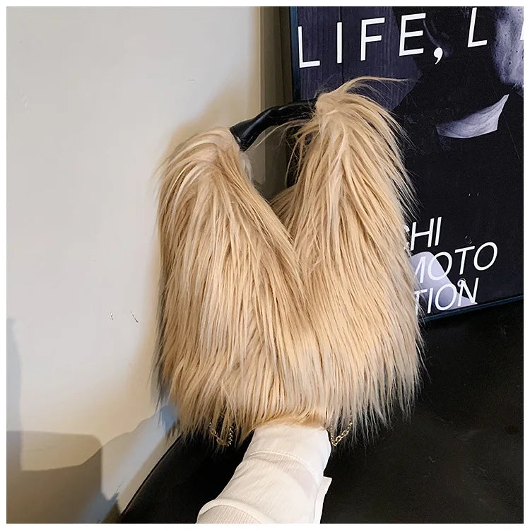 Khaki fluffy handbag held by a hand with a magazine in the background