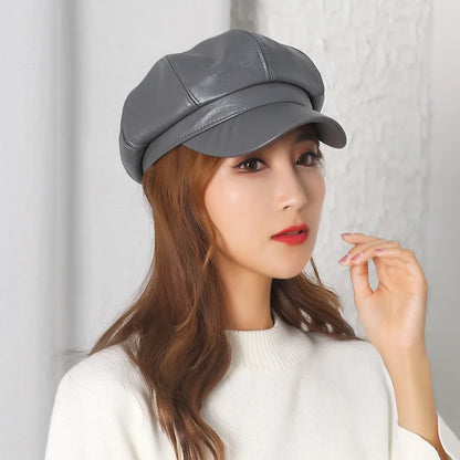 Woman wearing a grey leather cap against a light background