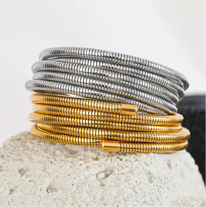 Stack of gold and silver bracelets on a textured surface