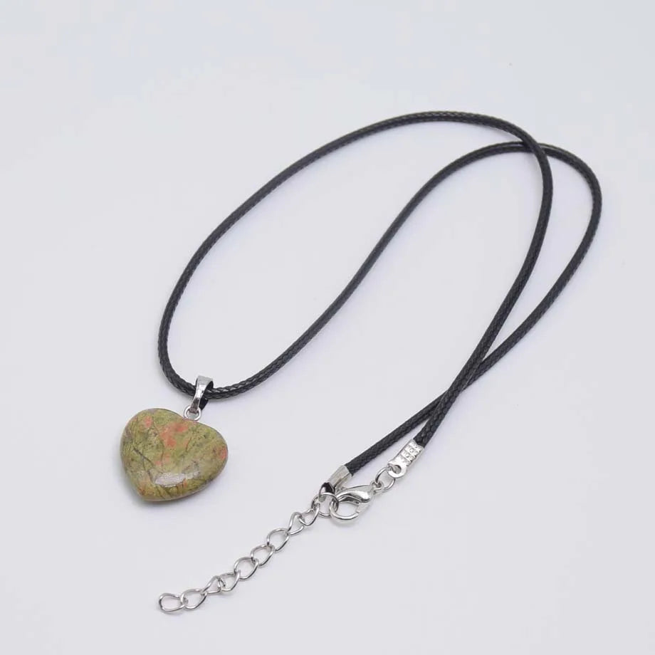 Necklace with a green stone pendant on a black cord against a white background