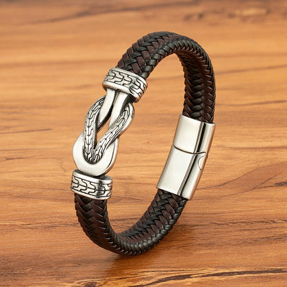 Brown braided leather bracelet with silver clasp on a wooden surface