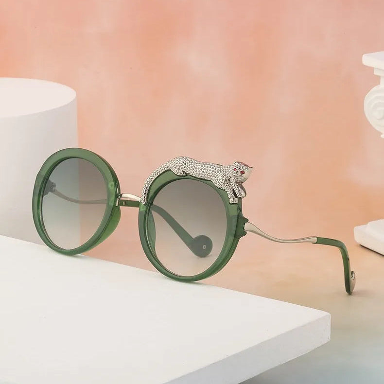 Green sunglasses with a decorative leopard on a white surface with a pinkish background