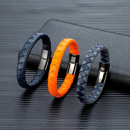 Three braided leather bracelets in dark blue, orange and grey and dark blue colours on the black background