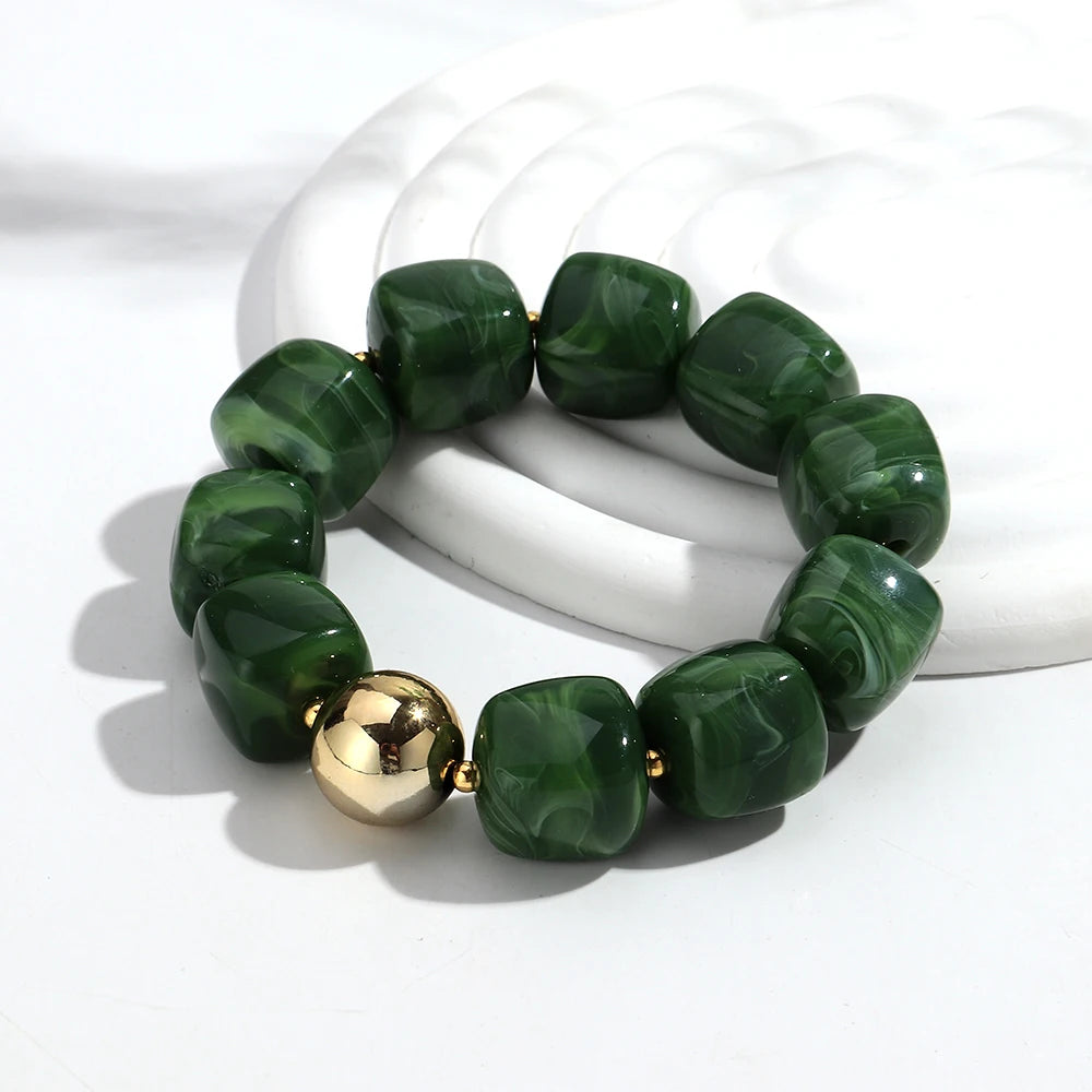 Green beaded bracelet with a gold accent on a white background