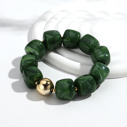 Green beaded bracelet with a gold accent on a white background