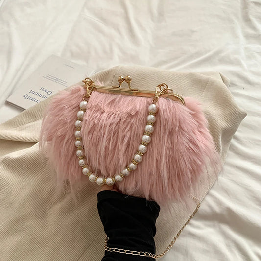 Pink fluffy handbag with pearl chain held by a gloved hand on a light background