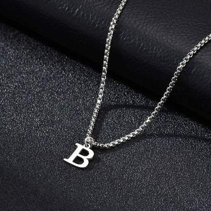 Silver necklace with a 'B' pendant on a black textured surface