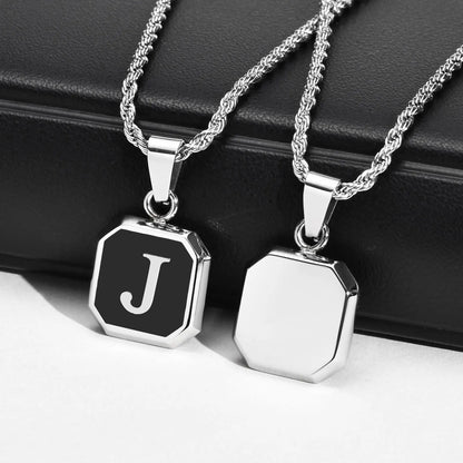 Two silver necklaces with hexagonal pendants on a black surface