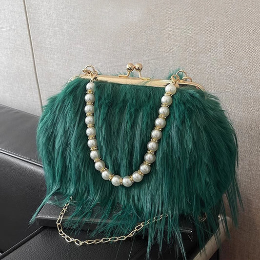 Green feathered handbag with pearl chain on a textured surface