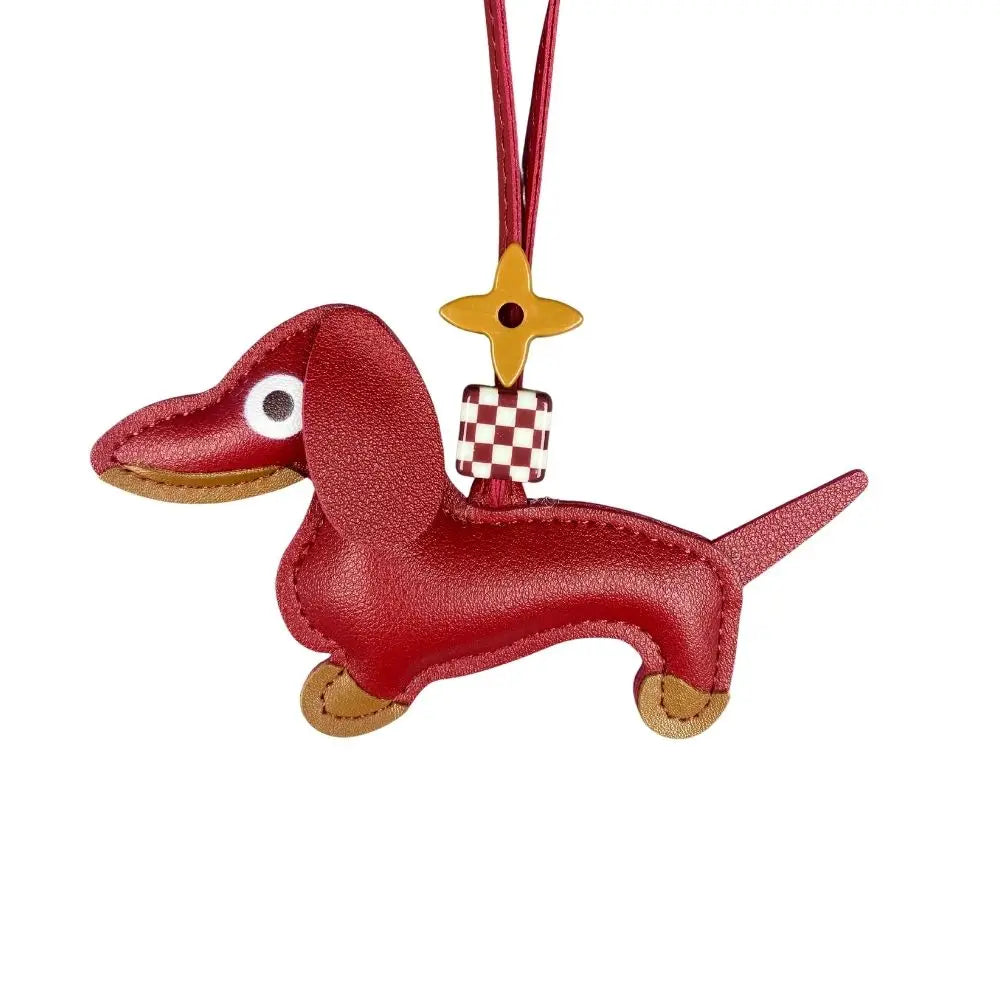 Red dachshund-shaped bag charm with a checkered bag and yellow star on a white background