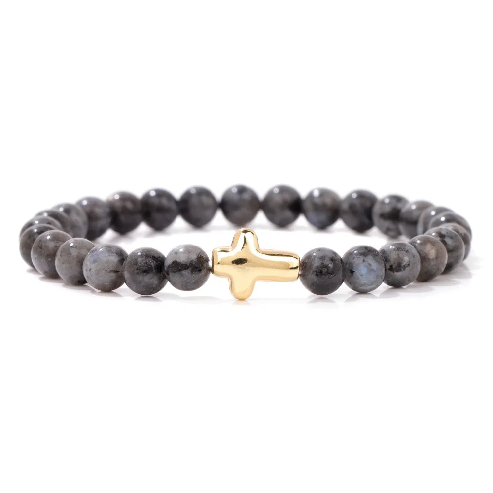 Grey beaded bracelet with a gold cross charm on a white background