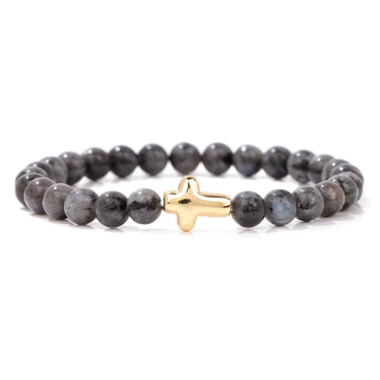Grey beaded bracelet with a gold cross charm on a white background