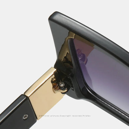 Close-up of a pair of sunglasses showing the hinge and frame detail on a light grey background.