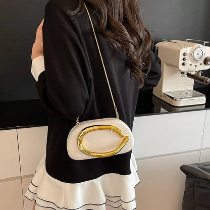 Person wearing a black and white dress with a gold-handled handbag in a kitchen setting.