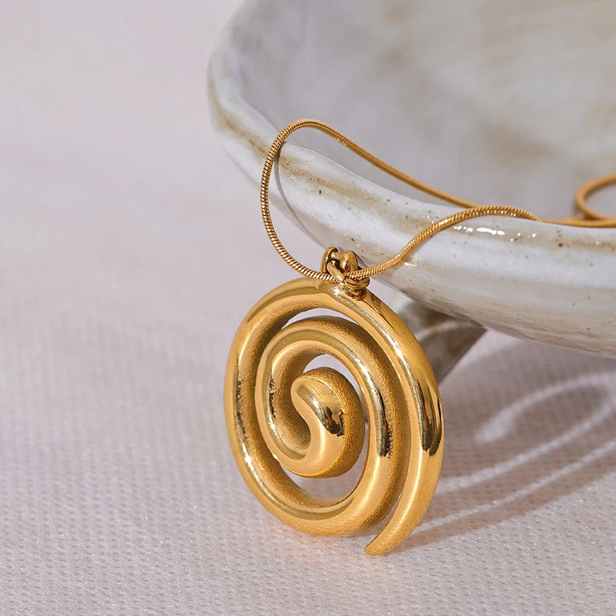 Gold spiral pendant on a light background.