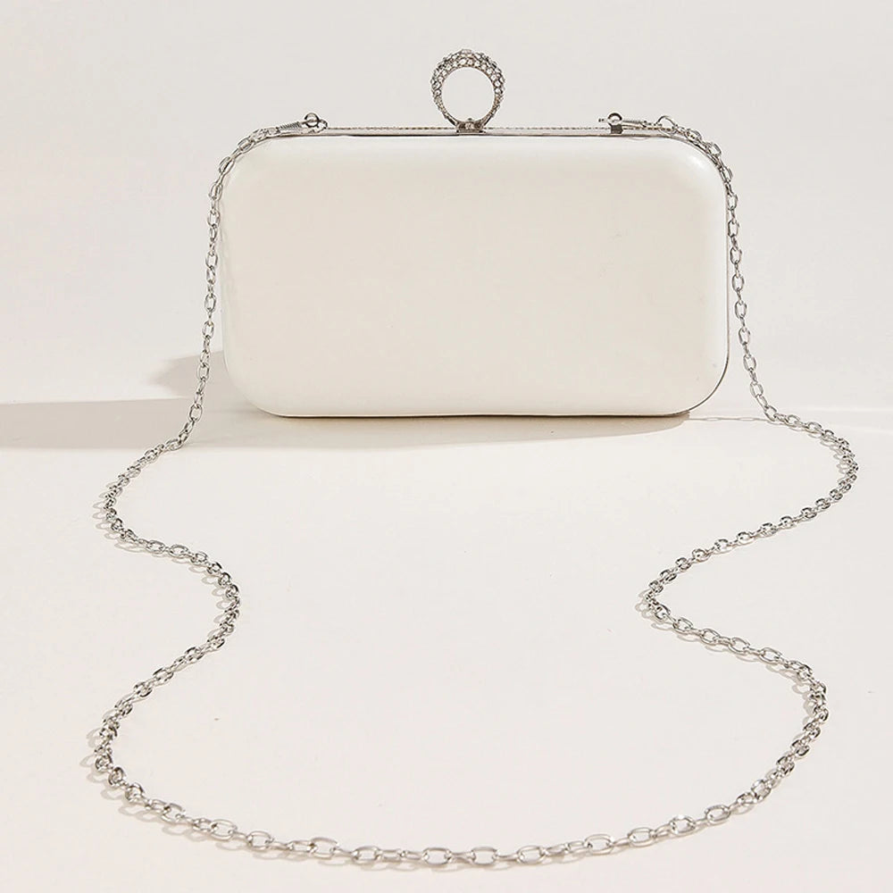 White clutch bag with a chain strap on a light beige background